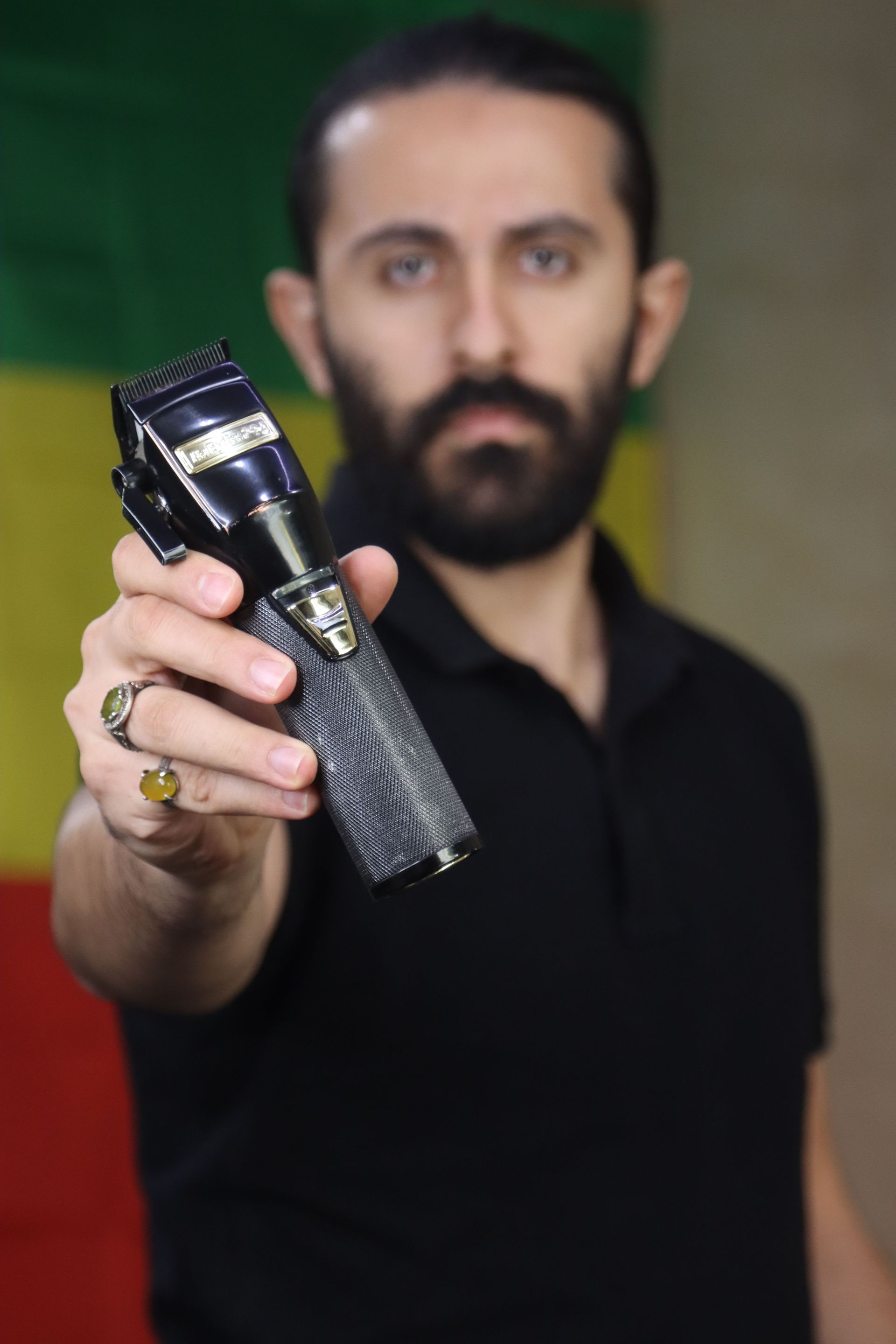 Close-up of a man holding a hair trimmer with a colorful background. Perfect for grooming themes.