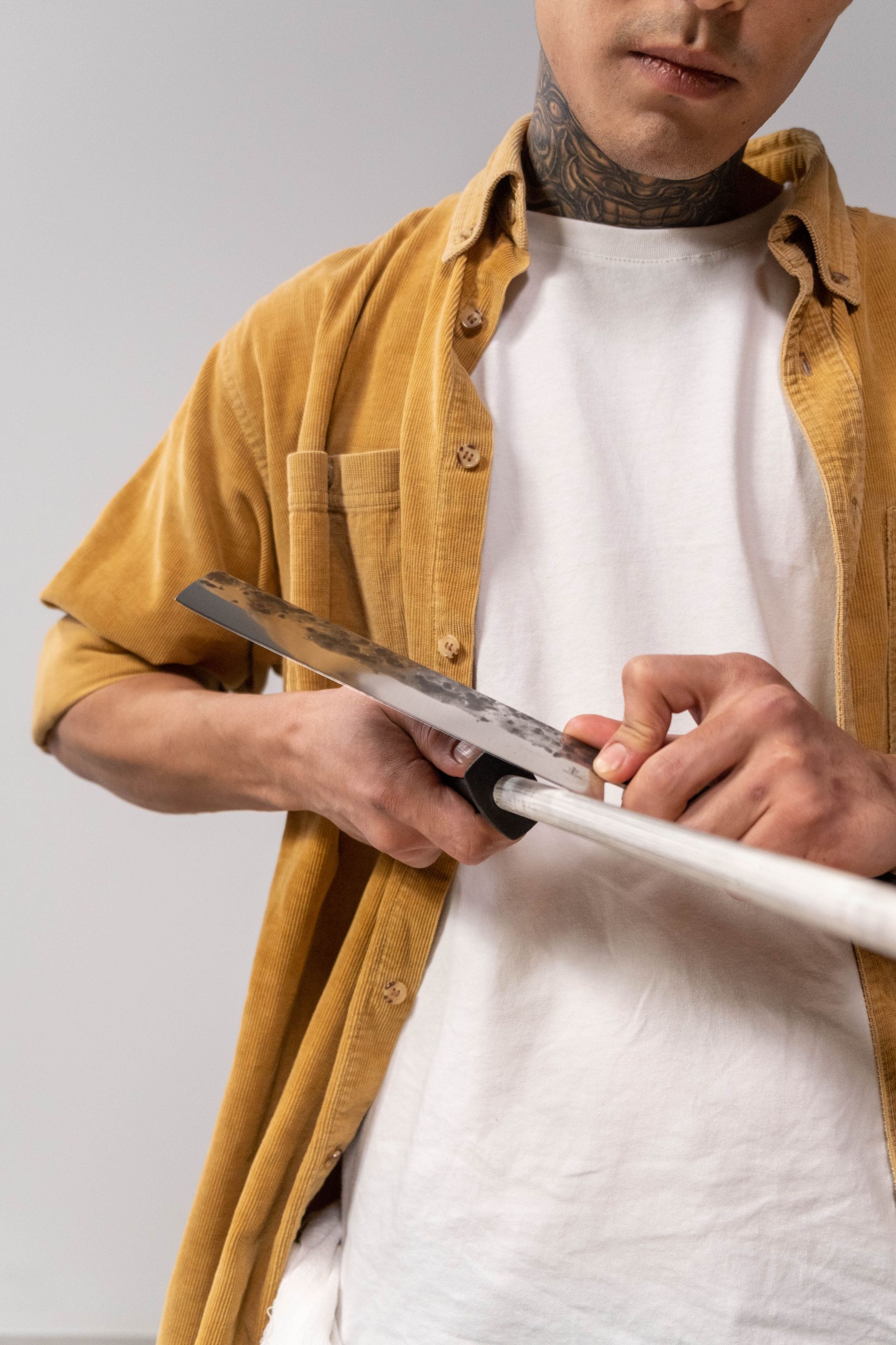 Close-up of a man sharpening a kitchen knife with honing steel, focusing on technique and precision.